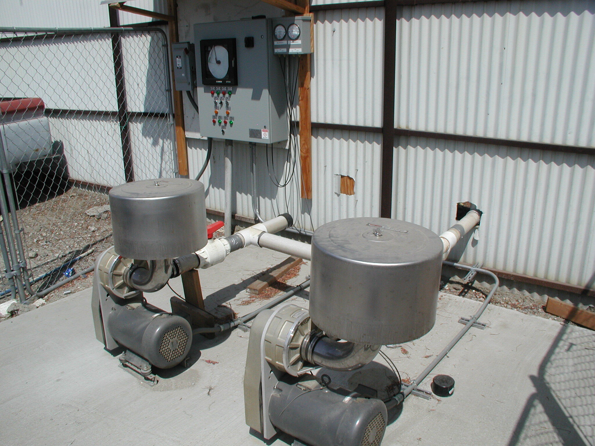 Twin stainless steel blower units and control panel at an outdoor remediation site