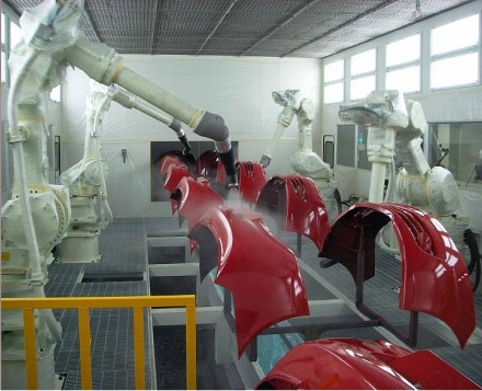 Robotic arms painting automotive parts on a production line