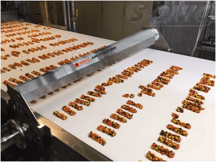 Food products moving beneath a sanitary Sonic air knife